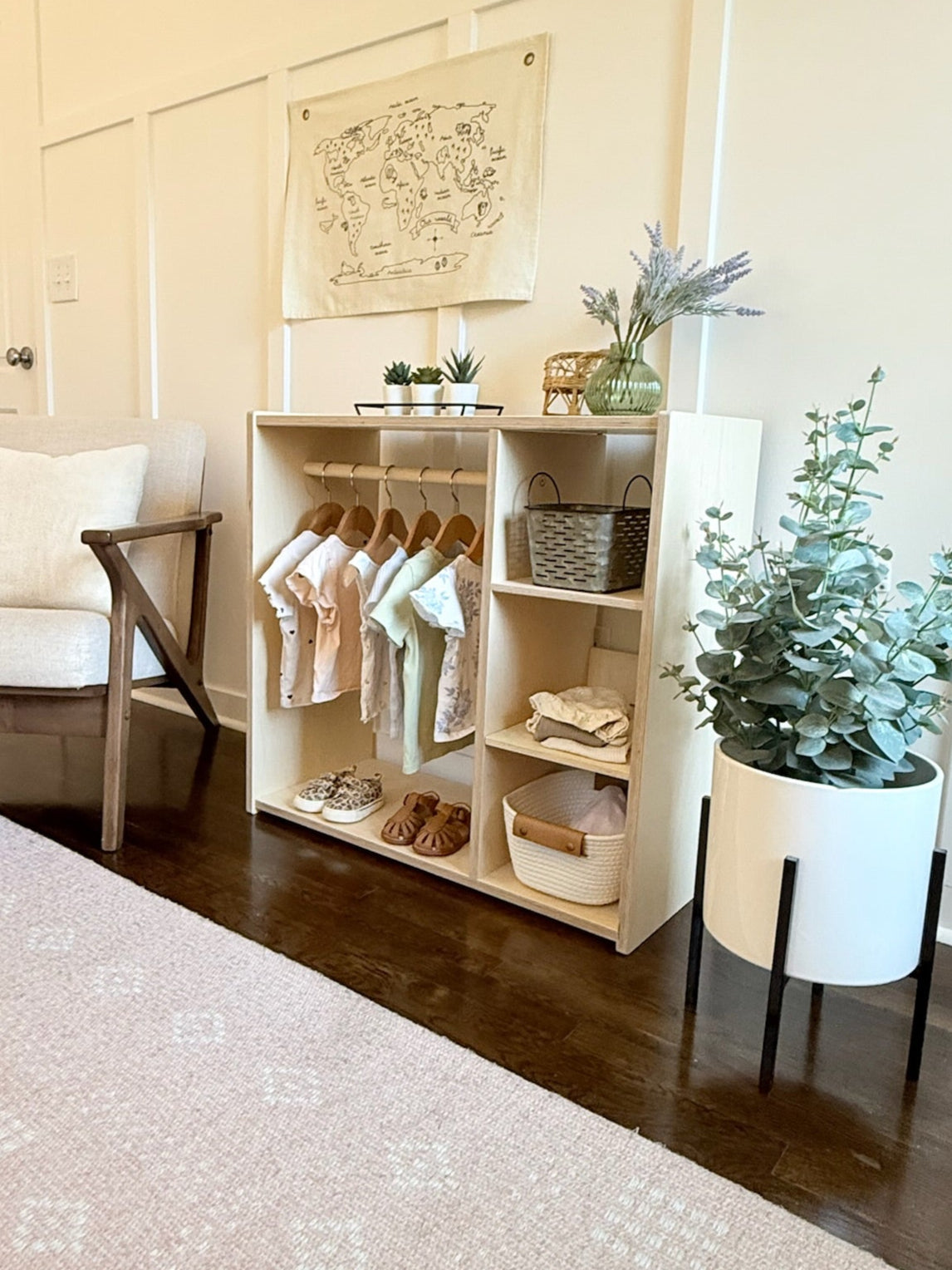 Nursery room with a white crib, chair, and shelves with baby clothes and items.