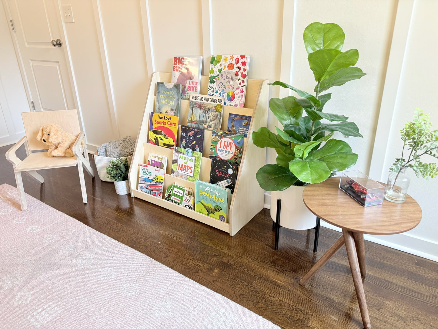 Bookshelf with colorful books in a room with a wooden floor and white walls.