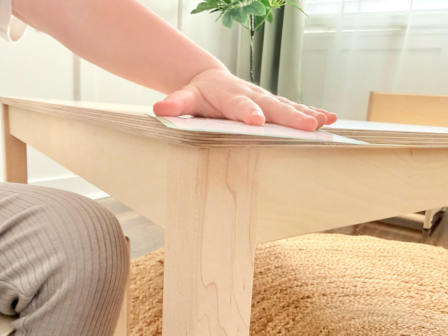 Child's hand on a wooden Montessori table with a blurred background