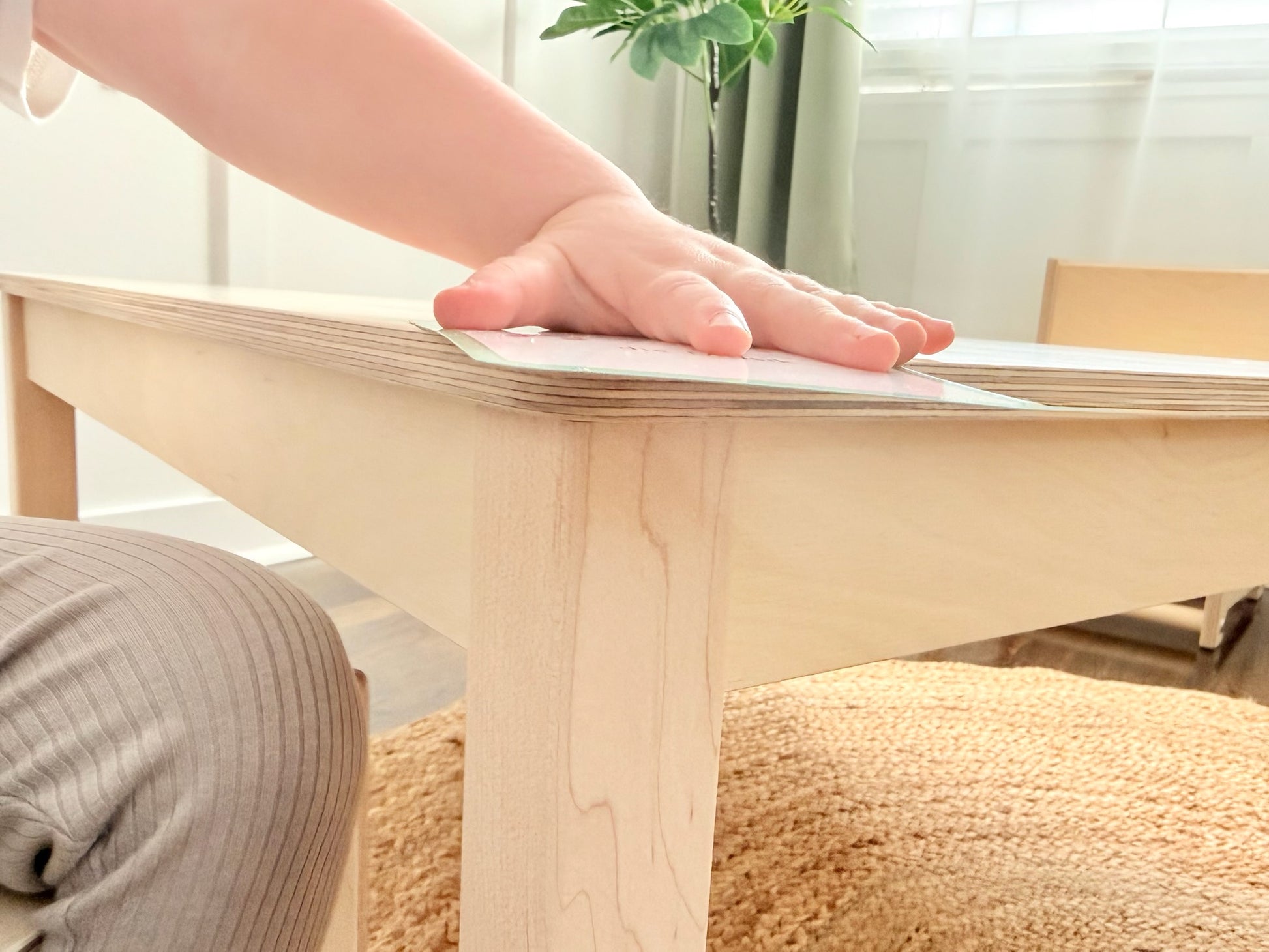 Child's hand on a wooden Montessori table with a blurred background
