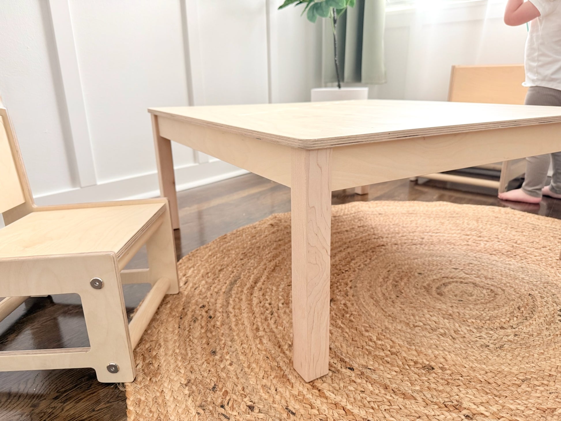 Montessori style wooden table and chair set on a textured rug with a neutral background
