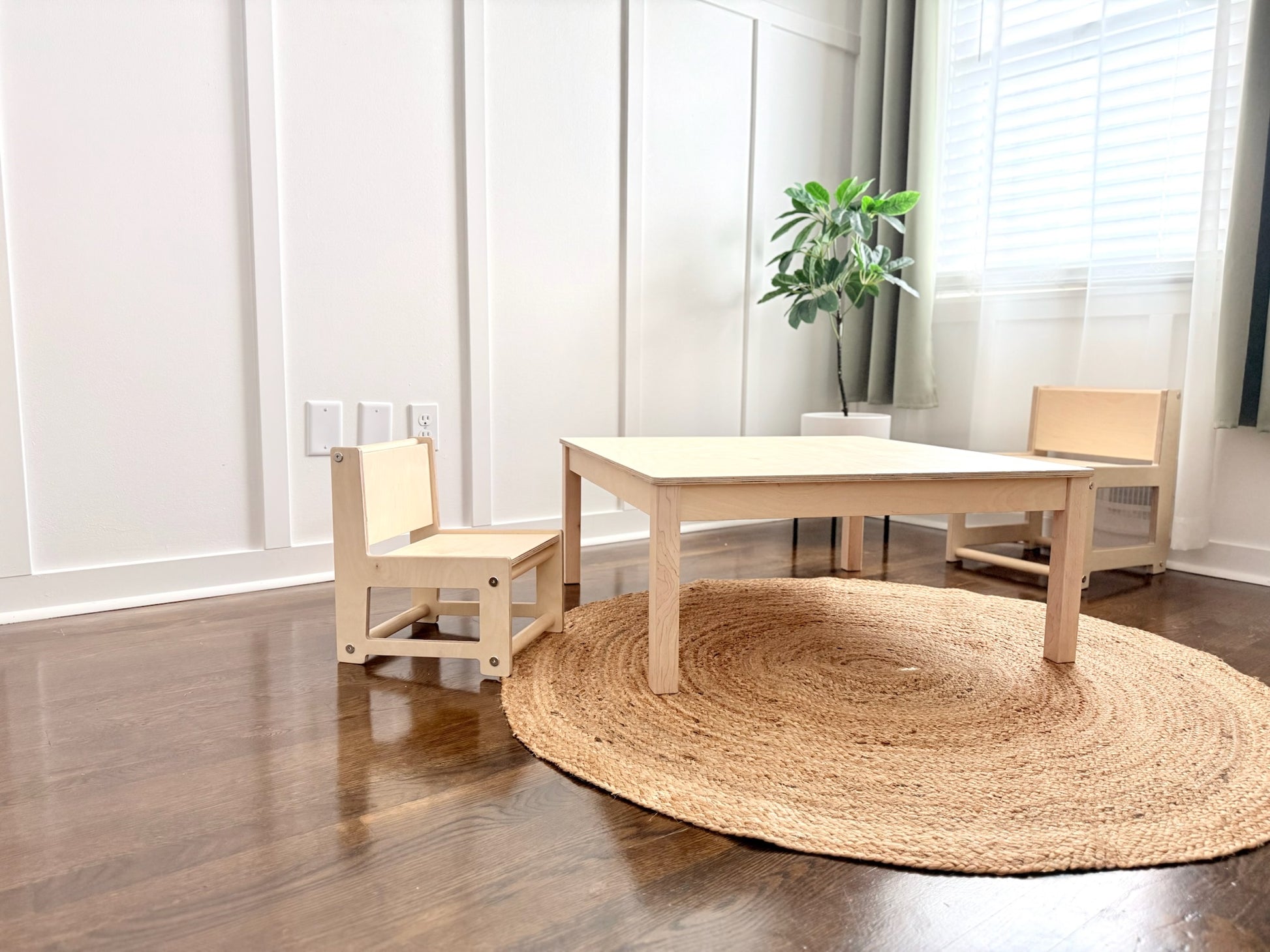 Wooden table and chairs in a room with a round jute rug on the floor.