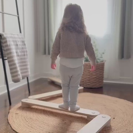 Toddler playing on wooden balance beam set in bright room