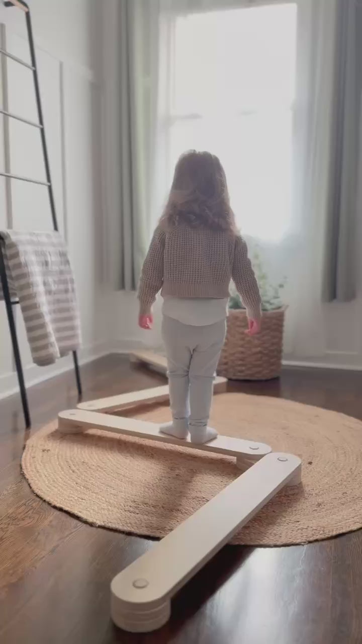 Toddler playing on wooden balance beam set in bright room